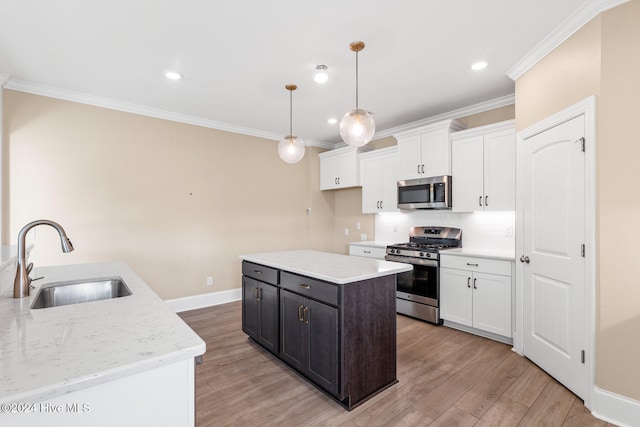 kitchen with sink, light wood-type flooring, hanging light fixtures, stainless steel appliances, and white cabinets