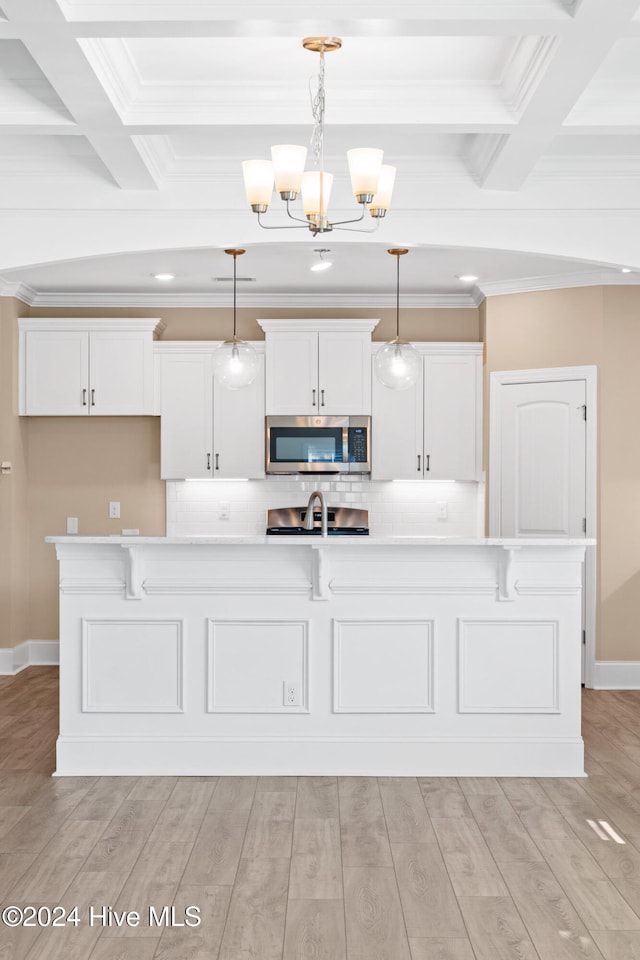 kitchen with white cabinets, pendant lighting, light wood-type flooring, and an island with sink