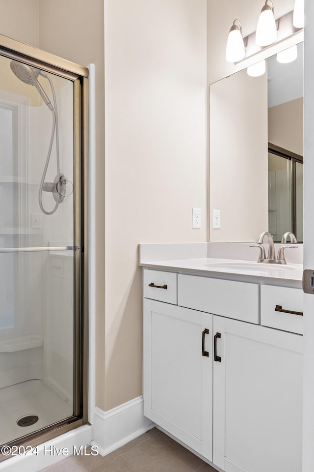 bathroom featuring a shower with door, vanity, and tile patterned floors