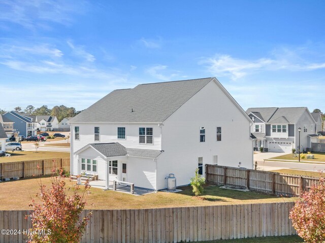 46 Covey Ct, Hampstead, NC 28443 - back of property featuring roof with shingles, a lawn, a residential view, a patio area, and a fenced backyard