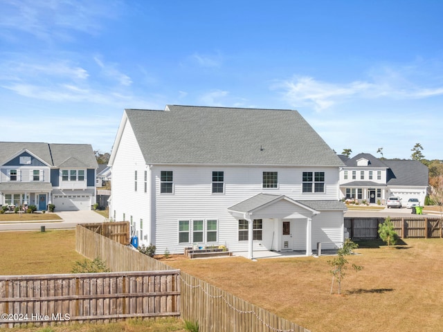 rear view of property with a patio, a yard, and a garage