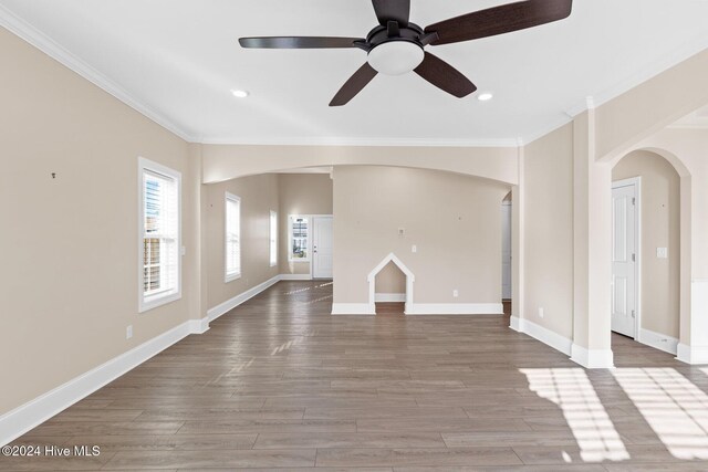 46 Covey Ct, Hampstead, NC 28443 - unfurnished living room featuring crown molding, arched walkways, baseboards, and wood finished floors