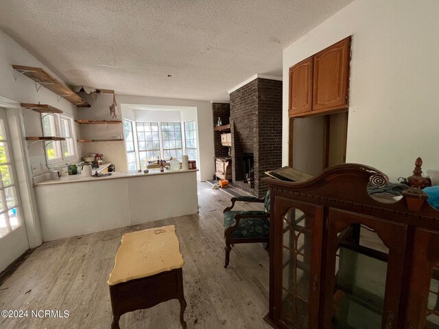 kitchen with a brick fireplace, a textured ceiling, and light hardwood / wood-style floors