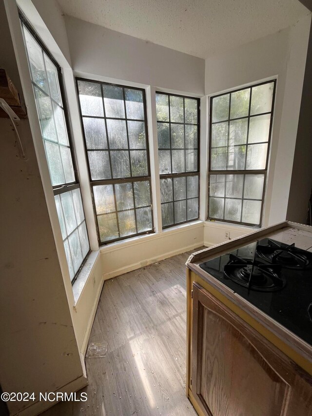 kitchen featuring light hardwood / wood-style floors, black range, and a textured ceiling