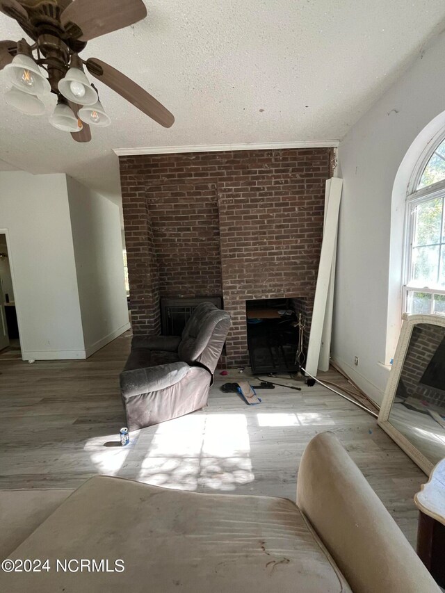 unfurnished living room with ceiling fan, a textured ceiling, light hardwood / wood-style flooring, and a fireplace