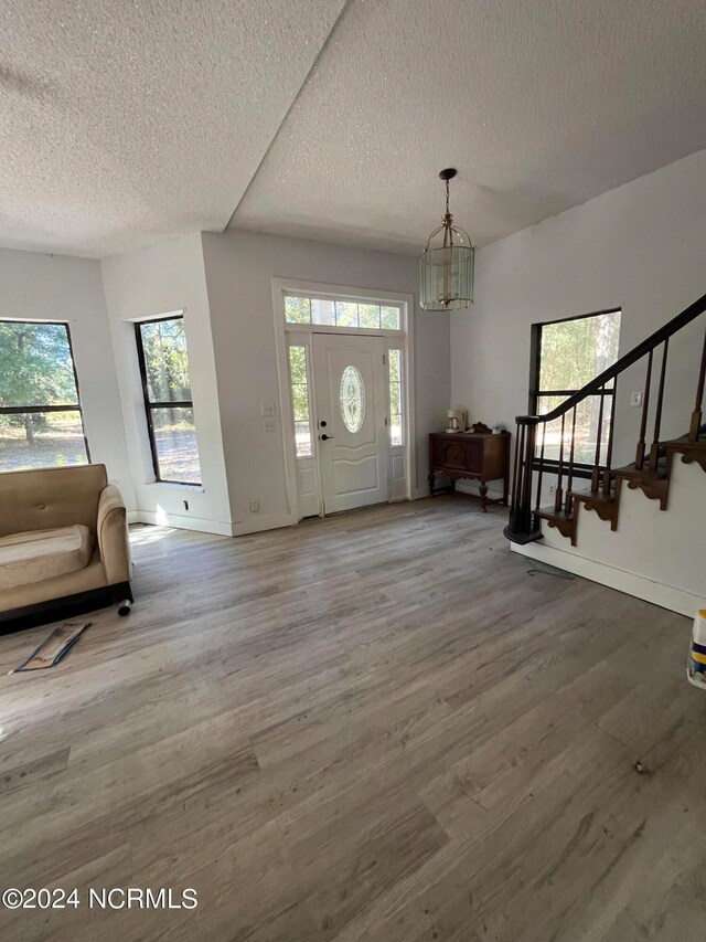 foyer with hardwood / wood-style flooring, a textured ceiling, and an inviting chandelier