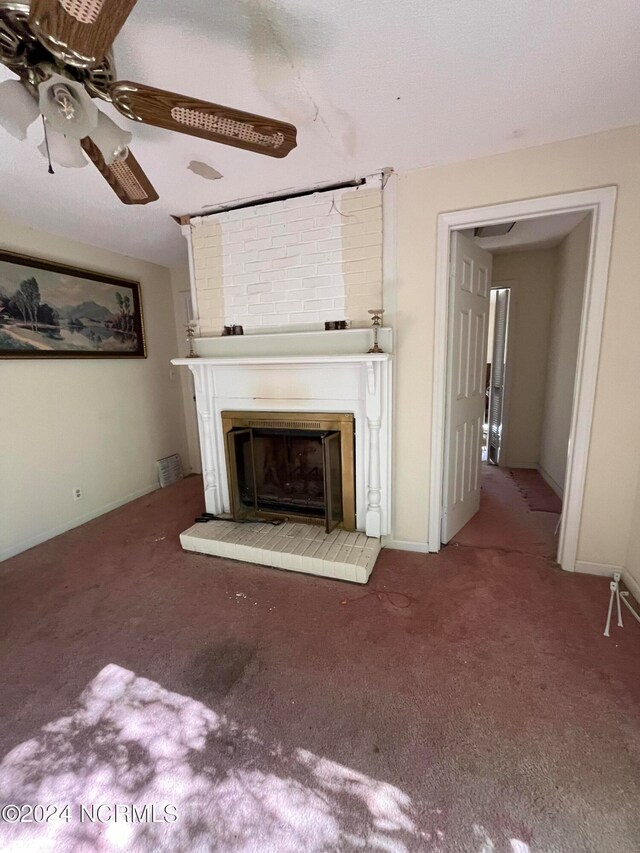 unfurnished living room with a large fireplace, carpet flooring, and ceiling fan