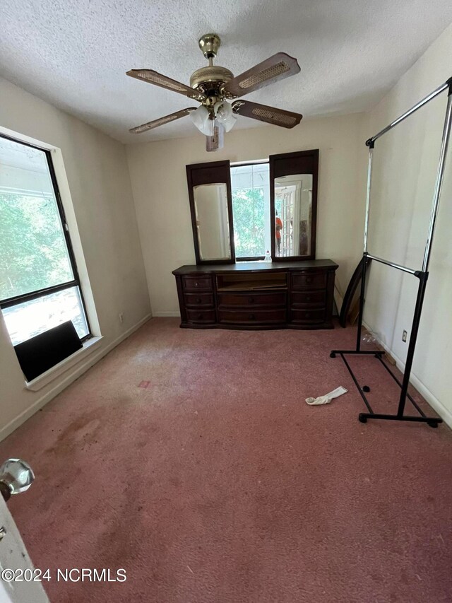 unfurnished bedroom with carpet floors, a textured ceiling, and ceiling fan