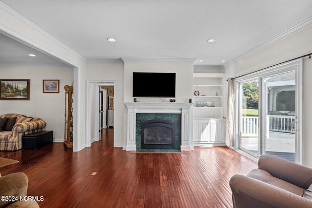 living room featuring built in features, ornamental molding, a fireplace, and dark hardwood / wood-style flooring