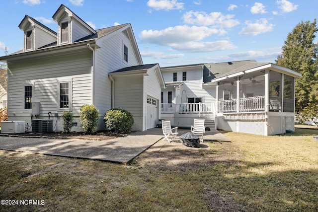 rear view of property featuring cooling unit, a lawn, and a sunroom