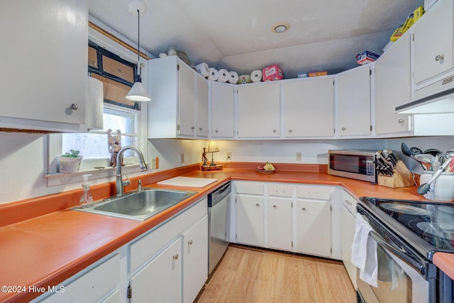 kitchen featuring sink, white cabinetry, hanging light fixtures, light wood-type flooring, and appliances with stainless steel finishes