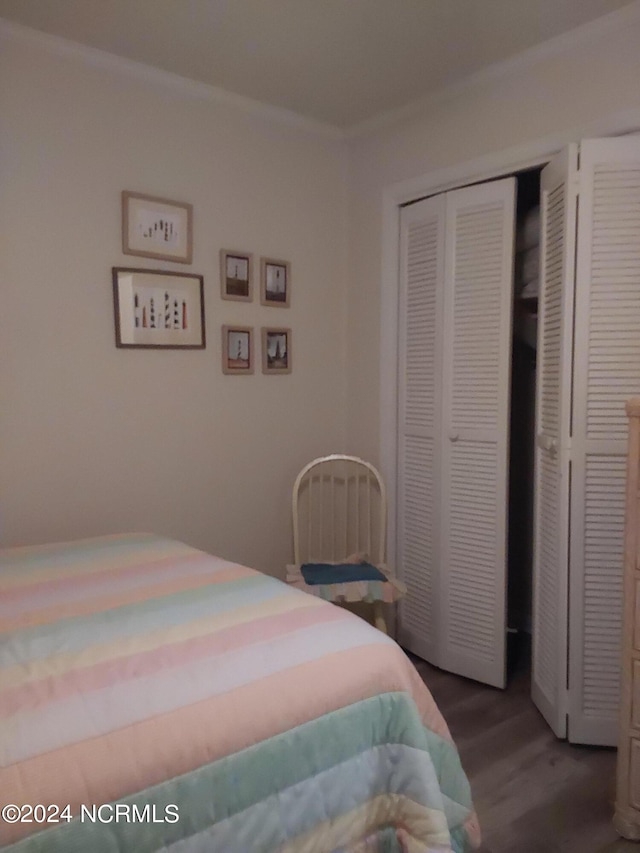 bedroom featuring a closet, wood-type flooring, and ornamental molding