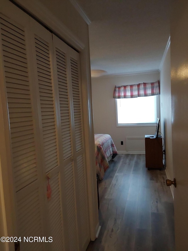 unfurnished bedroom featuring a closet, crown molding, and dark hardwood / wood-style floors