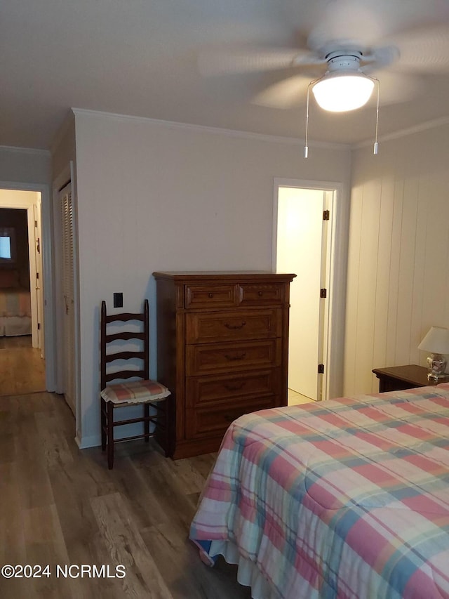 bedroom featuring dark wood-type flooring, crown molding, a closet, and ceiling fan