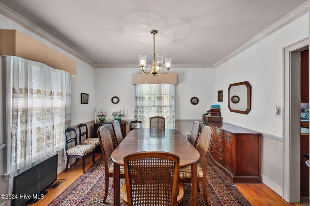 dining space with crown molding, light hardwood / wood-style flooring, and a chandelier