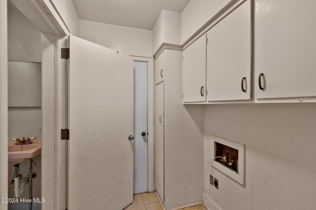 laundry area featuring cabinets, light tile patterned floors, hookup for a washing machine, electric dryer hookup, and sink