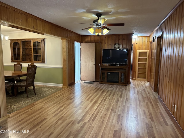 unfurnished living room with wooden walls, crown molding, a textured ceiling, and wood-type flooring