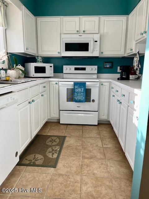 kitchen with white cabinets, white appliances, sink, and light tile patterned floors