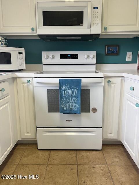 kitchen with light tile patterned floors, white appliances, and white cabinetry