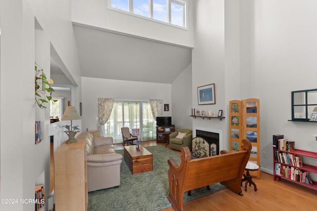 living room featuring a wealth of natural light, a towering ceiling, and wood-type flooring