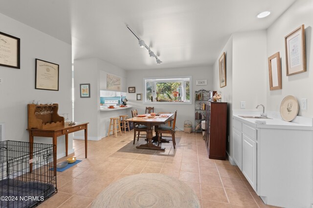 dining room featuring rail lighting, light tile patterned flooring, and sink