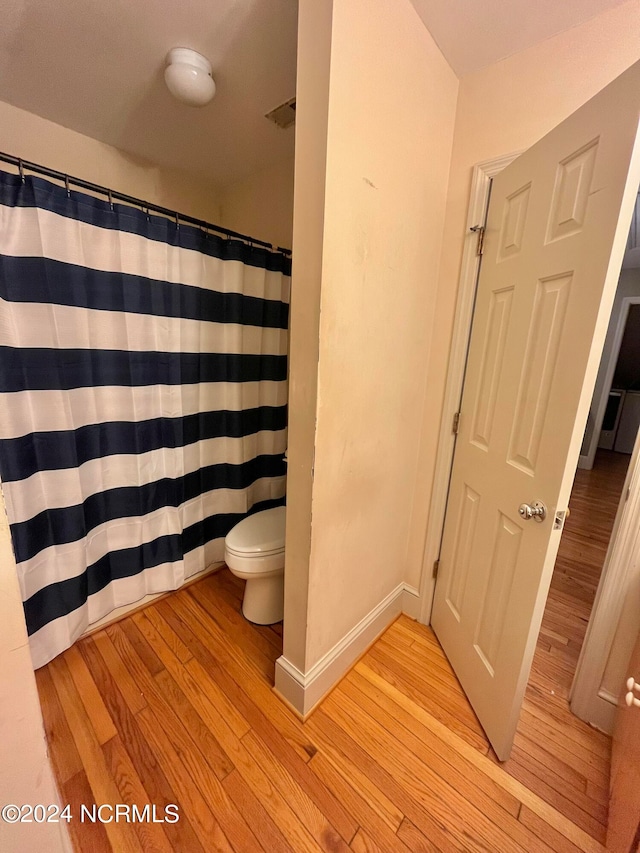 bathroom with toilet, hardwood / wood-style floors, and a shower with shower curtain