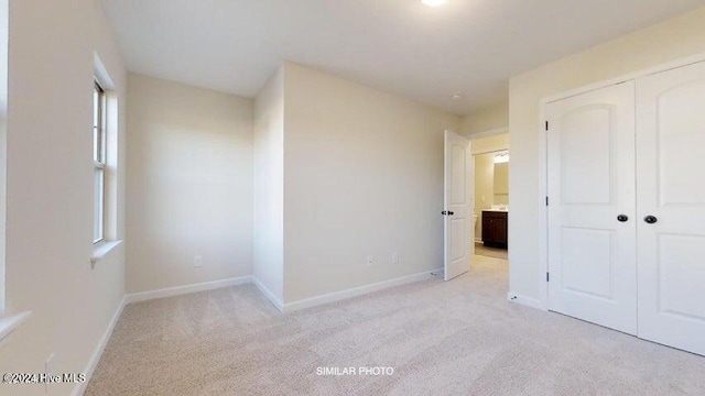 unfurnished bedroom featuring light colored carpet, multiple windows, and a closet