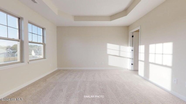 empty room with a tray ceiling and light carpet