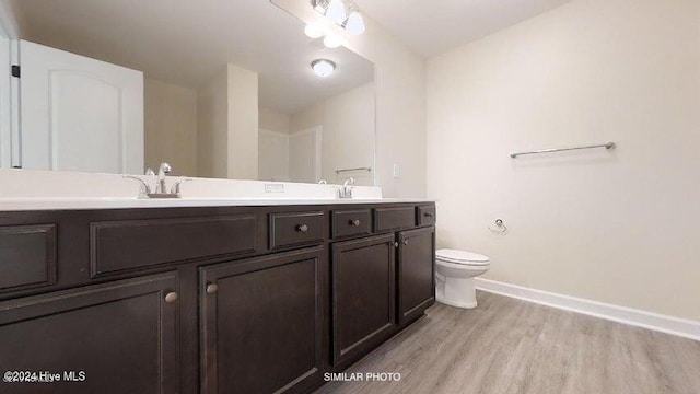 bathroom with wood-type flooring, vanity, and toilet