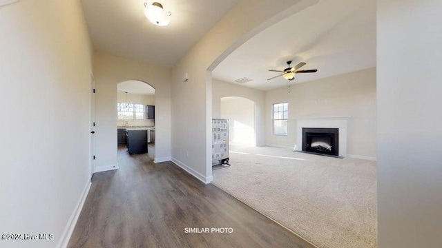 unfurnished living room with hardwood / wood-style flooring, ceiling fan, a wealth of natural light, and vaulted ceiling