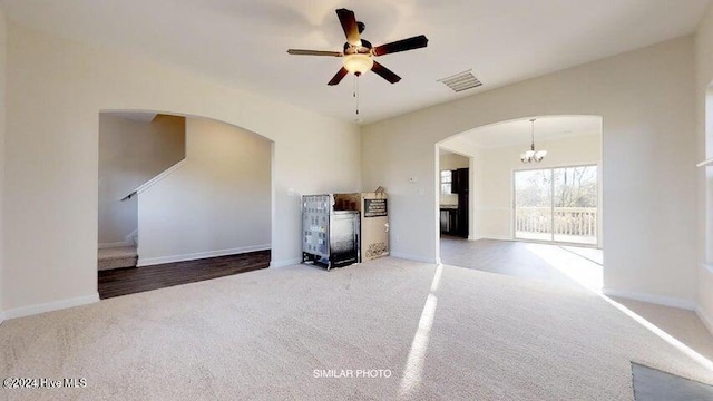 unfurnished living room with ceiling fan with notable chandelier and carpet floors