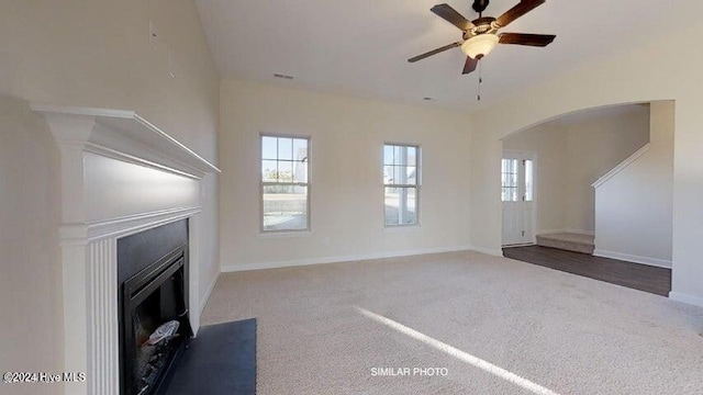 unfurnished living room featuring dark carpet and ceiling fan