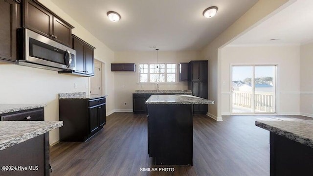 kitchen featuring light stone countertops, plenty of natural light, a kitchen island, and dark wood-type flooring