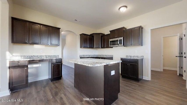 kitchen featuring a center island, dark hardwood / wood-style flooring, dark brown cabinetry, and light stone counters