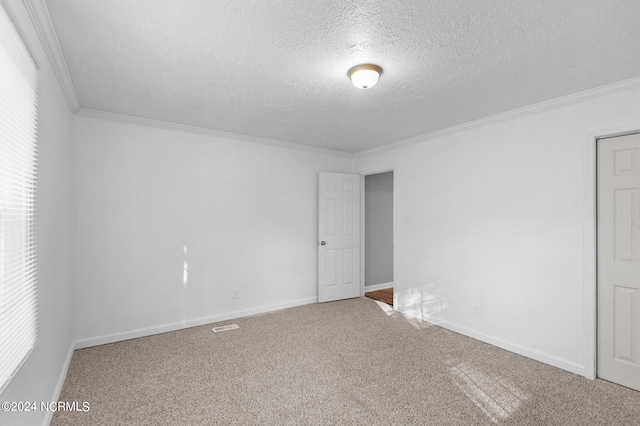 empty room featuring carpet flooring, ornamental molding, and a textured ceiling