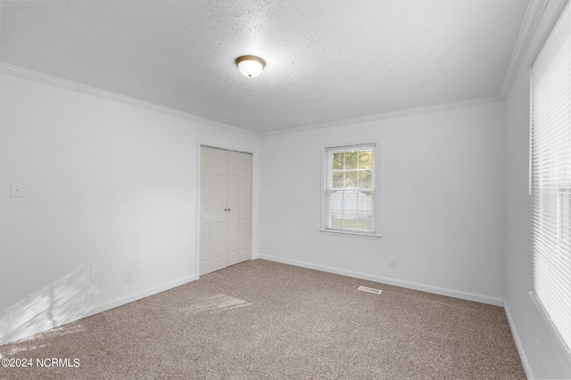 spare room featuring carpet flooring, a textured ceiling, and ornamental molding