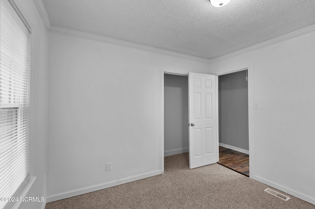 empty room featuring carpet flooring, a textured ceiling, and ornamental molding