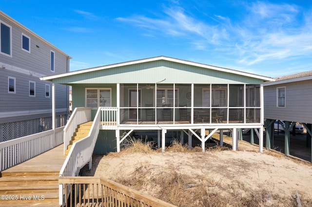 rear view of property with a sunroom and stairway