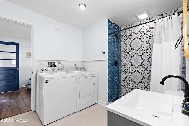 laundry area with a sink, wainscoting, washing machine and clothes dryer, and visible vents