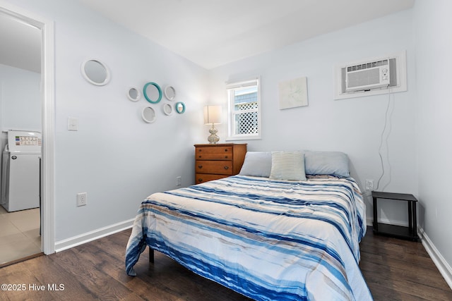 bedroom with an AC wall unit, fridge, wood finished floors, and baseboards