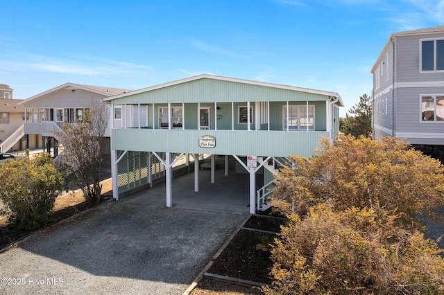 view of front of home with stairs, a carport, and concrete driveway