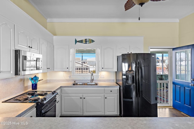 kitchen with black appliances, white cabinetry, ornamental molding, and a sink