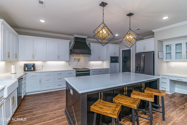 kitchen with premium range hood, appliances with stainless steel finishes, hanging light fixtures, and white cabinets