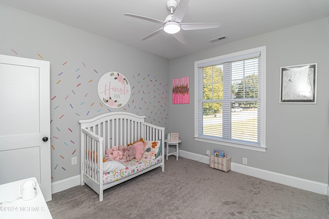 bedroom featuring a nursery area, ceiling fan, and carpet flooring