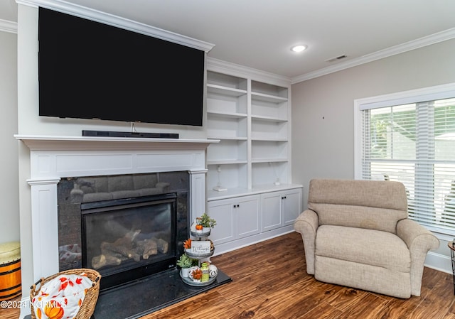 sitting room with a tiled fireplace, ornamental molding, and dark wood-type flooring