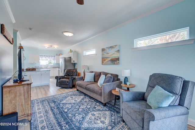 living room featuring ornamental molding, light wood-type flooring, and plenty of natural light