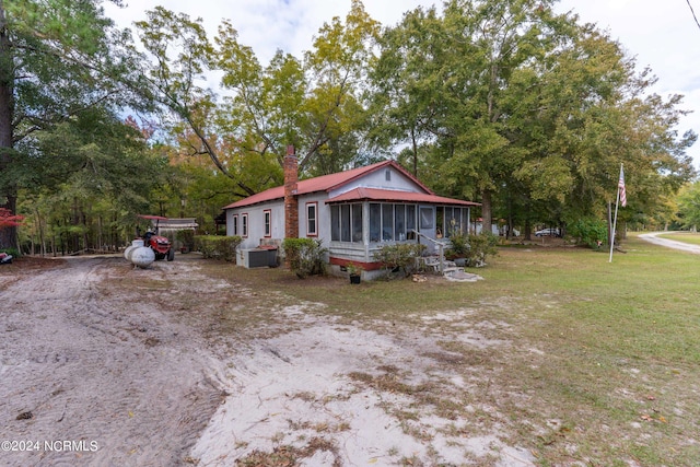 view of home's exterior featuring a sunroom, a lawn, a chimney, and metal roof