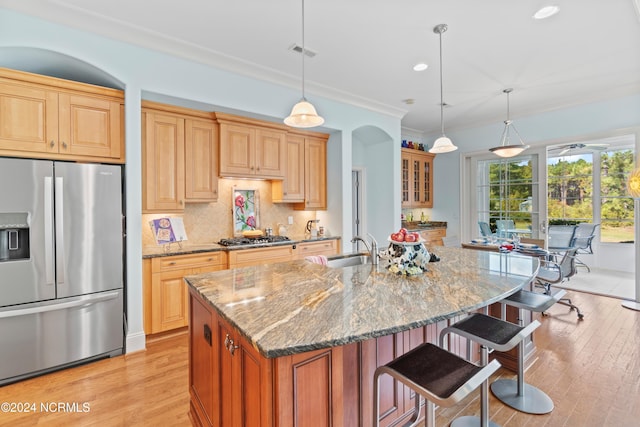 kitchen featuring light stone counters, decorative light fixtures, a kitchen island with sink, and appliances with stainless steel finishes