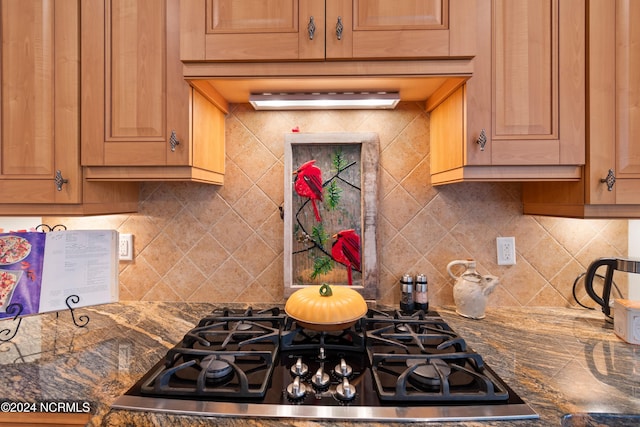 kitchen featuring backsplash, dark stone countertops, and gas stovetop