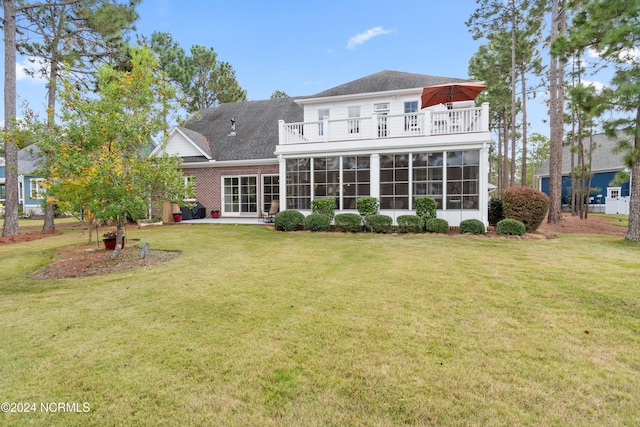 rear view of house featuring a balcony, a sunroom, and a lawn